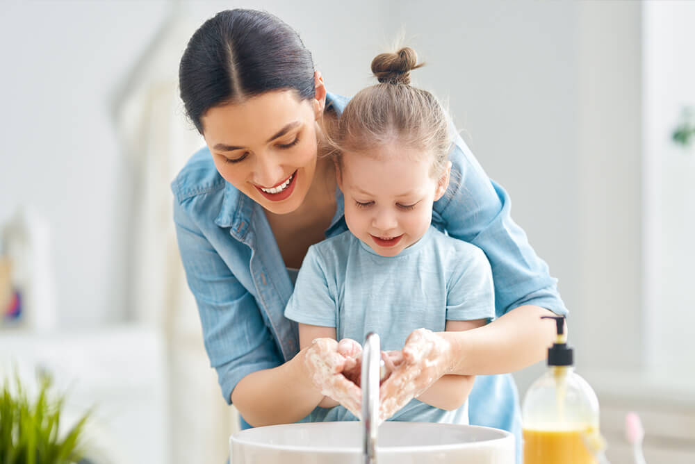 A woman and young girl washing their hands